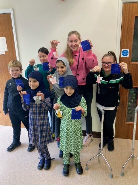Young Quilters hold up their blue embroidered hearts which bear messages from Terrence Higgins Trust staff, and will form part of the finished quilt.