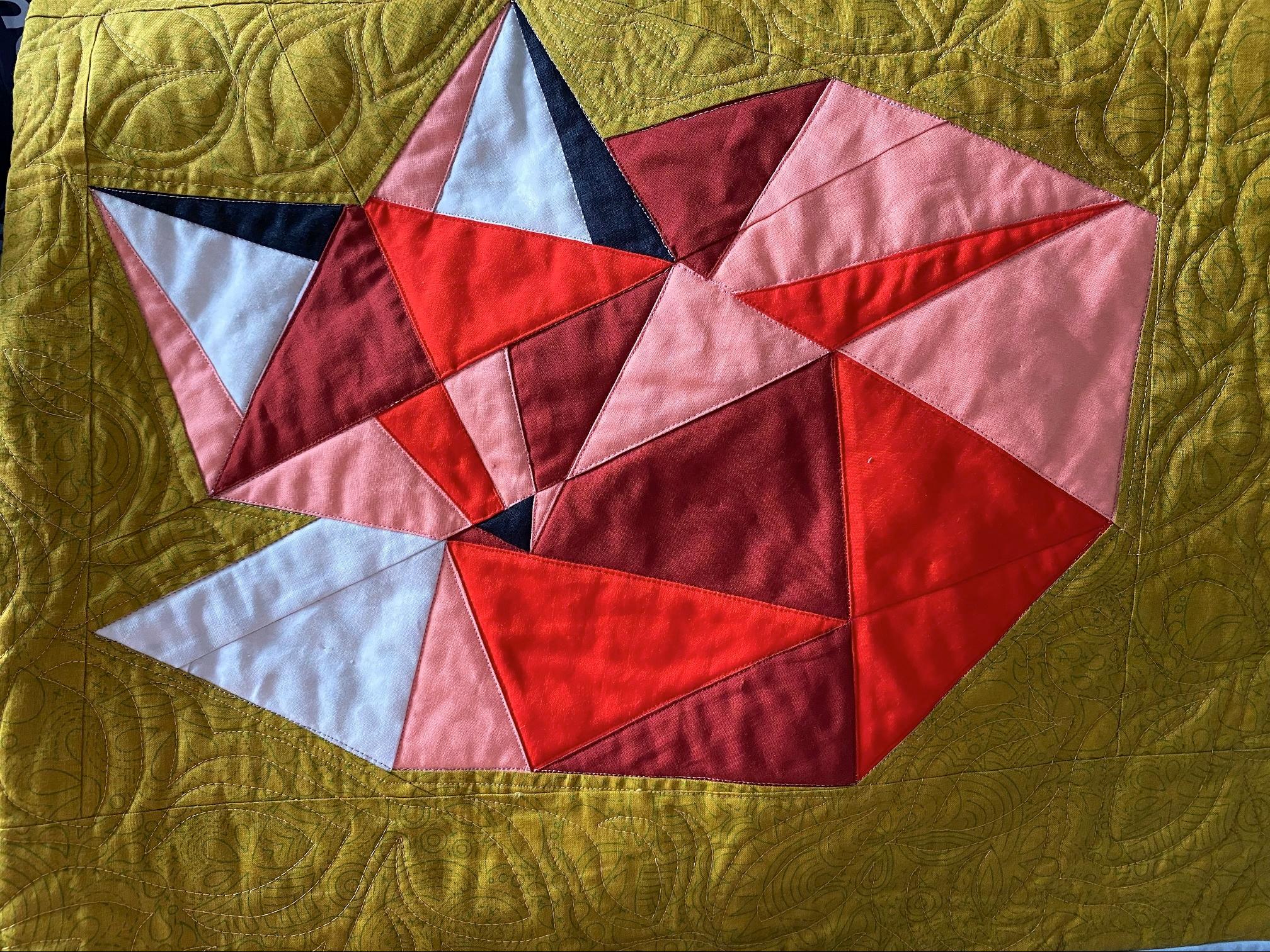 Detail image of quilt depicting a fox laid on a green ground, with quilting done in a leaf pattern.