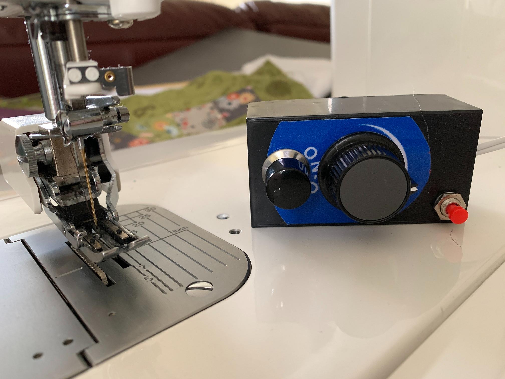 Close up image of a sewing machine bed with a special control panel to allow hand instead of foot control.