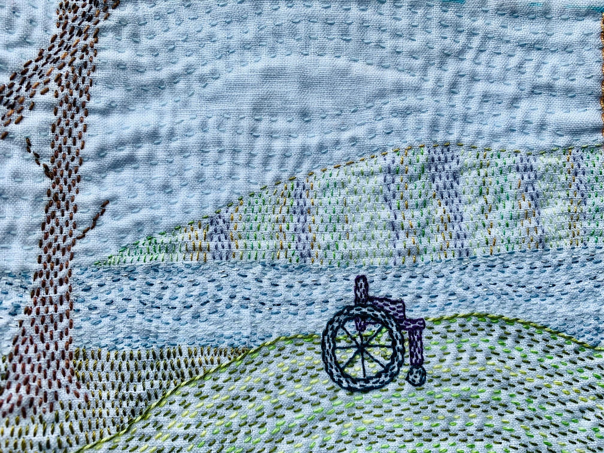 Image shows a kantha stitched scene depicting a wheelchair on the shore of a lake.
