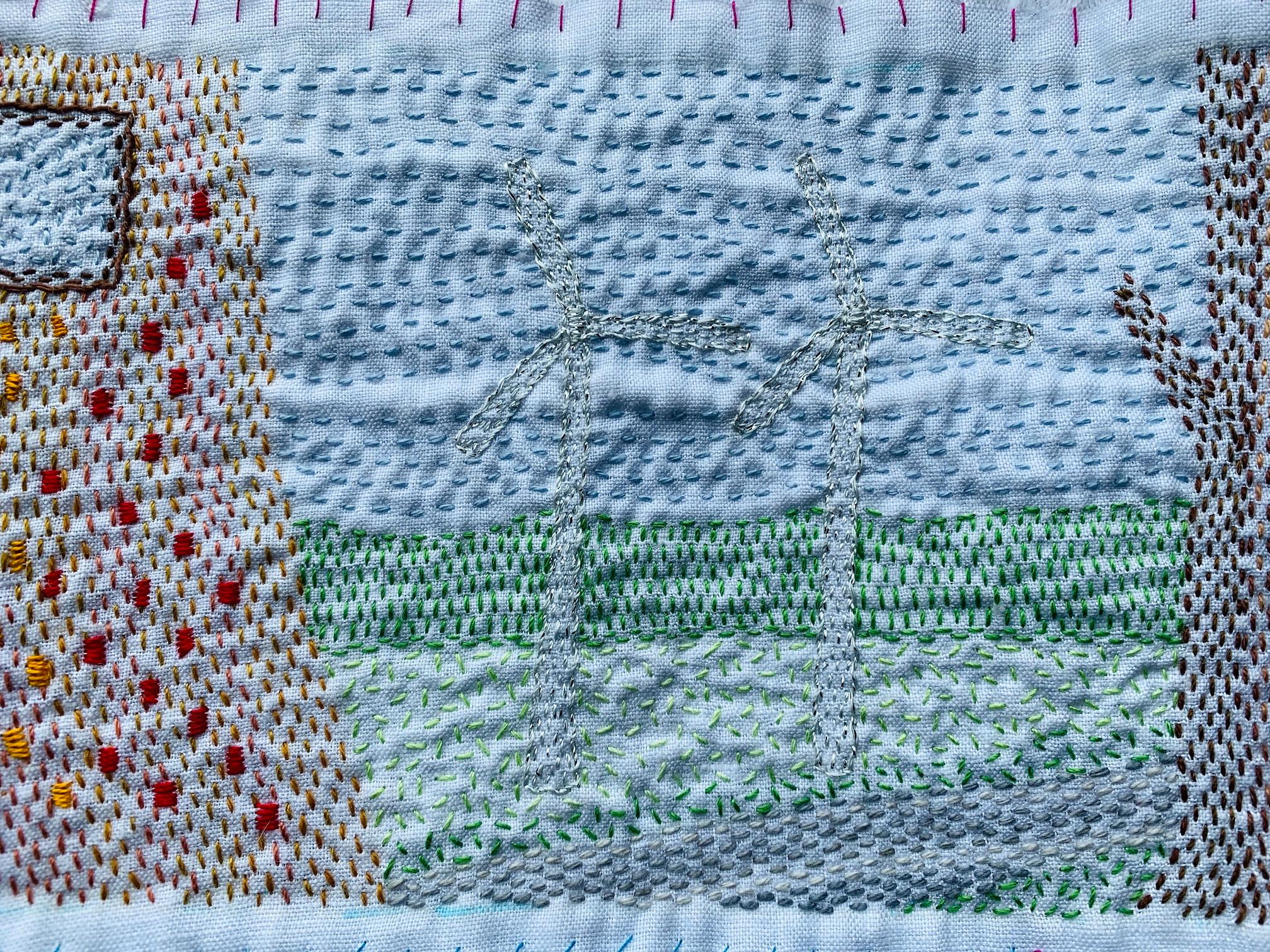 Image shows a kantha stitched scene of wind turbines on a blue fabric.