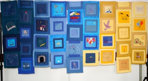Image shows a quilt made up of many individually hand embellished blocks in blue and yellow.