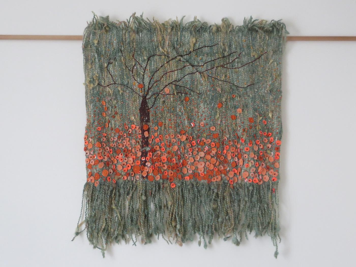 A stitched wool wall hanging in eau de nil on fabric, with fabric painted red and orange flowers with beads and embroidery.