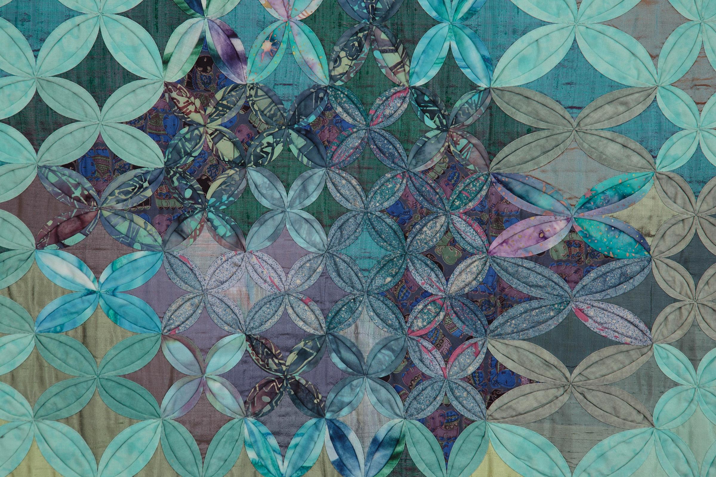 A cathedral windows quilt in purples, blues, turquoises and pinks.