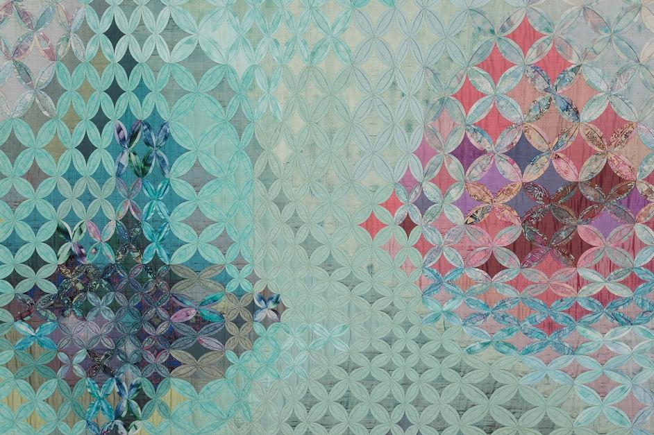 A landscape-format cathedral windows quilt in purples, blues, turquoises and pinks.