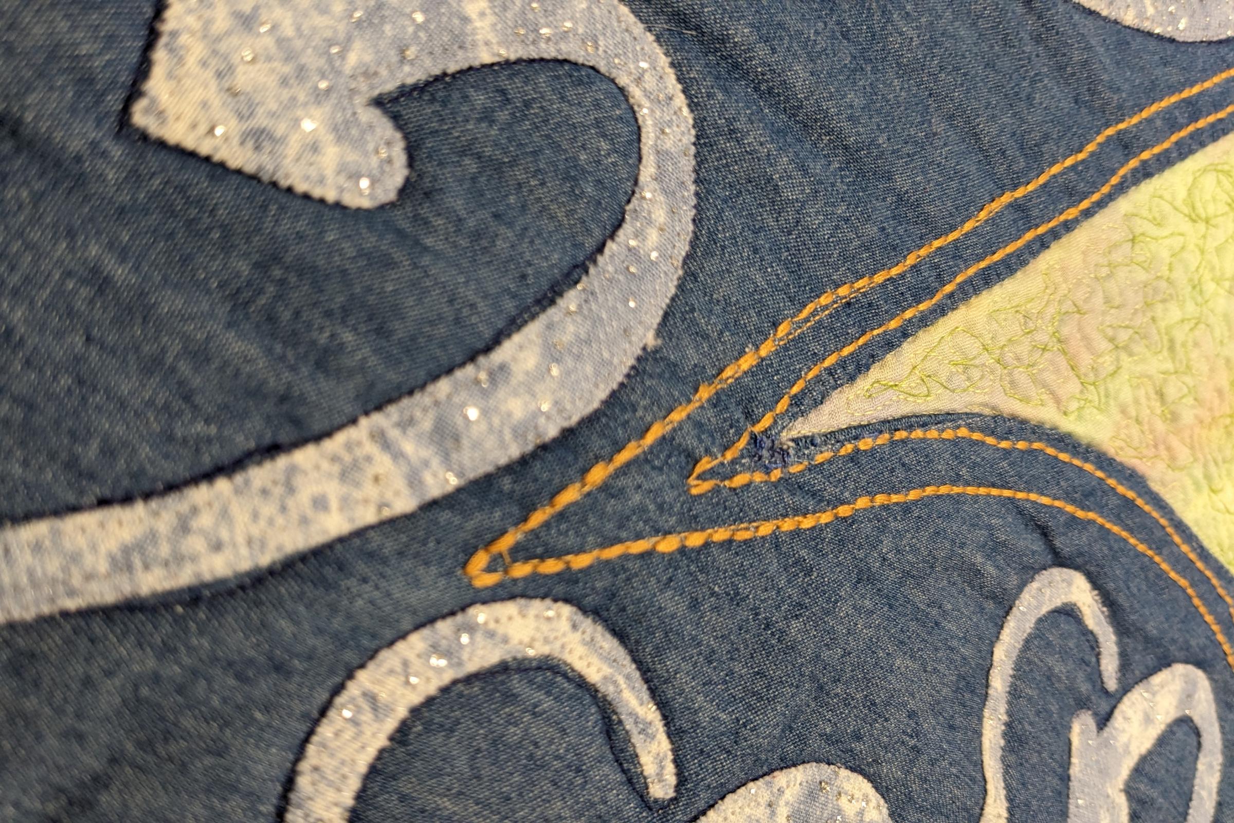 Close up image of a quilt using denim and applique.