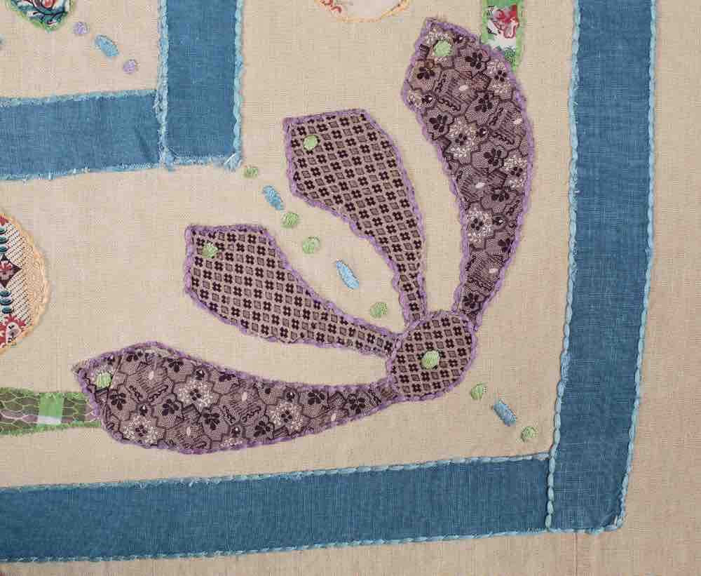 Quilt detail showing hand-finished appliqué and embroidery inspired by a 19th century heritage quilt