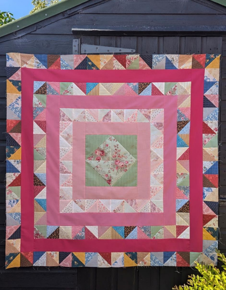Finished modern patchwork quilt inspired by traditional Cumbrian frame quilts, shown in bright contemporary fabrics