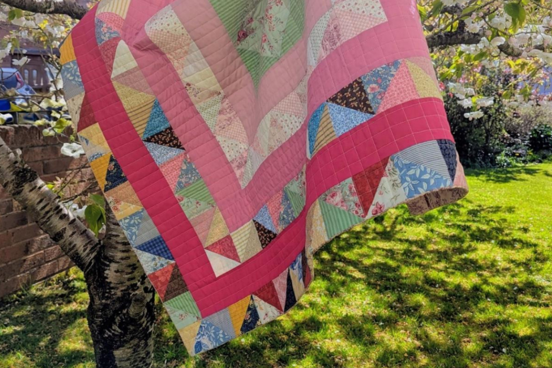 Modern Cumbrian frame quilt inspired by Bertha Mitchell&rsquo;s 1899 design, made with bright colours and floral fabrics