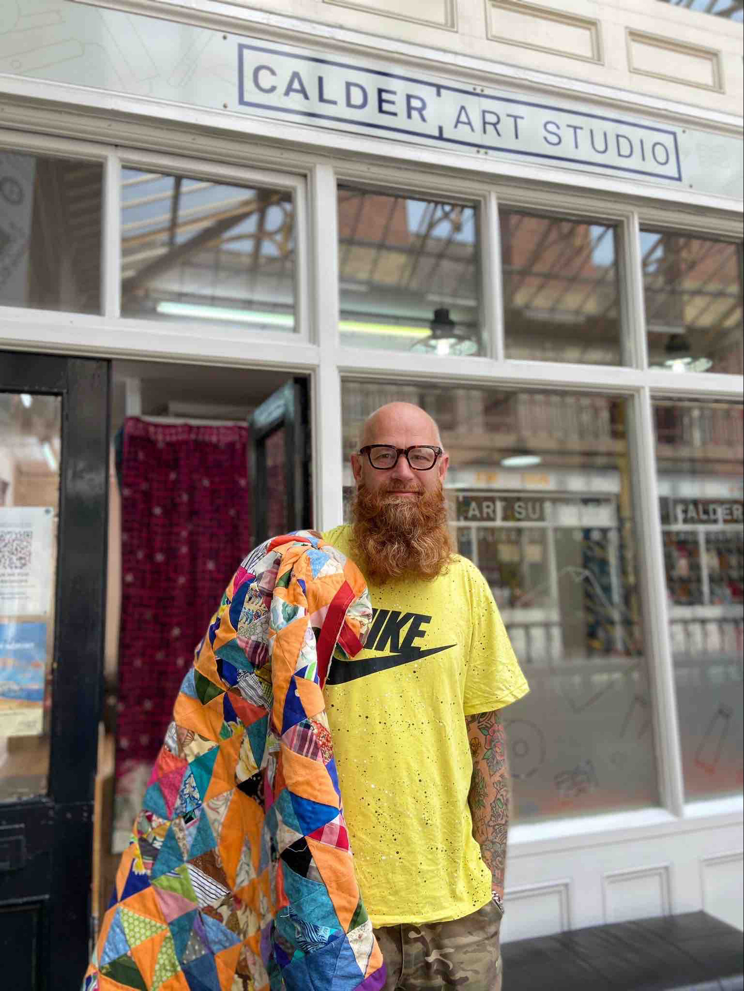 Chris English with quilt outside his community-focused Quilt Huddersfield project