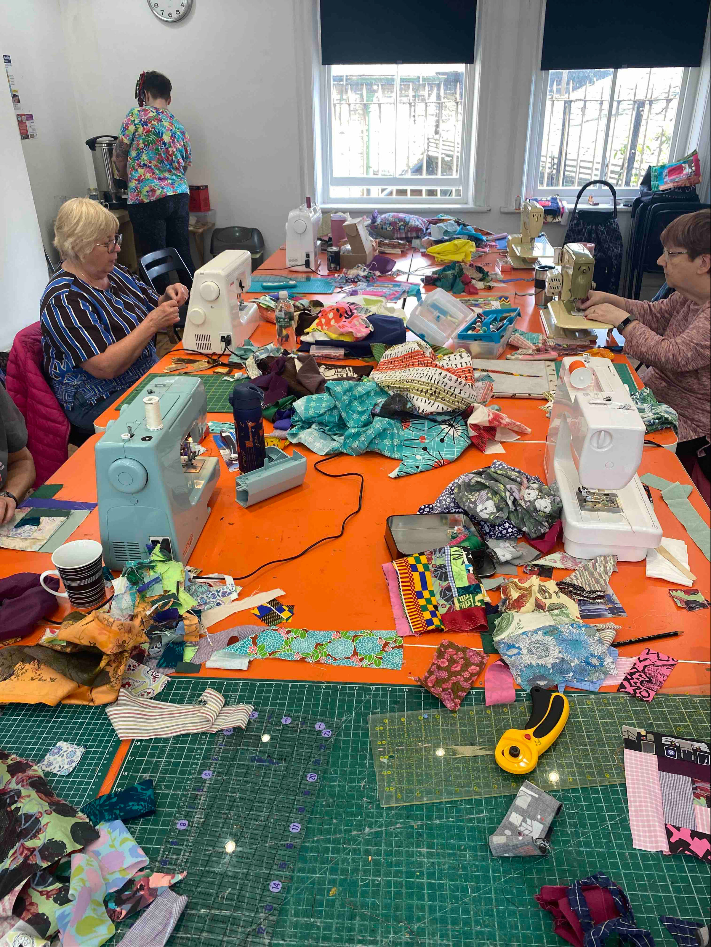 Women taking part in a Quilt Huddersfield workshop led by Chris English, learning quilting techniques using recycled fabrics