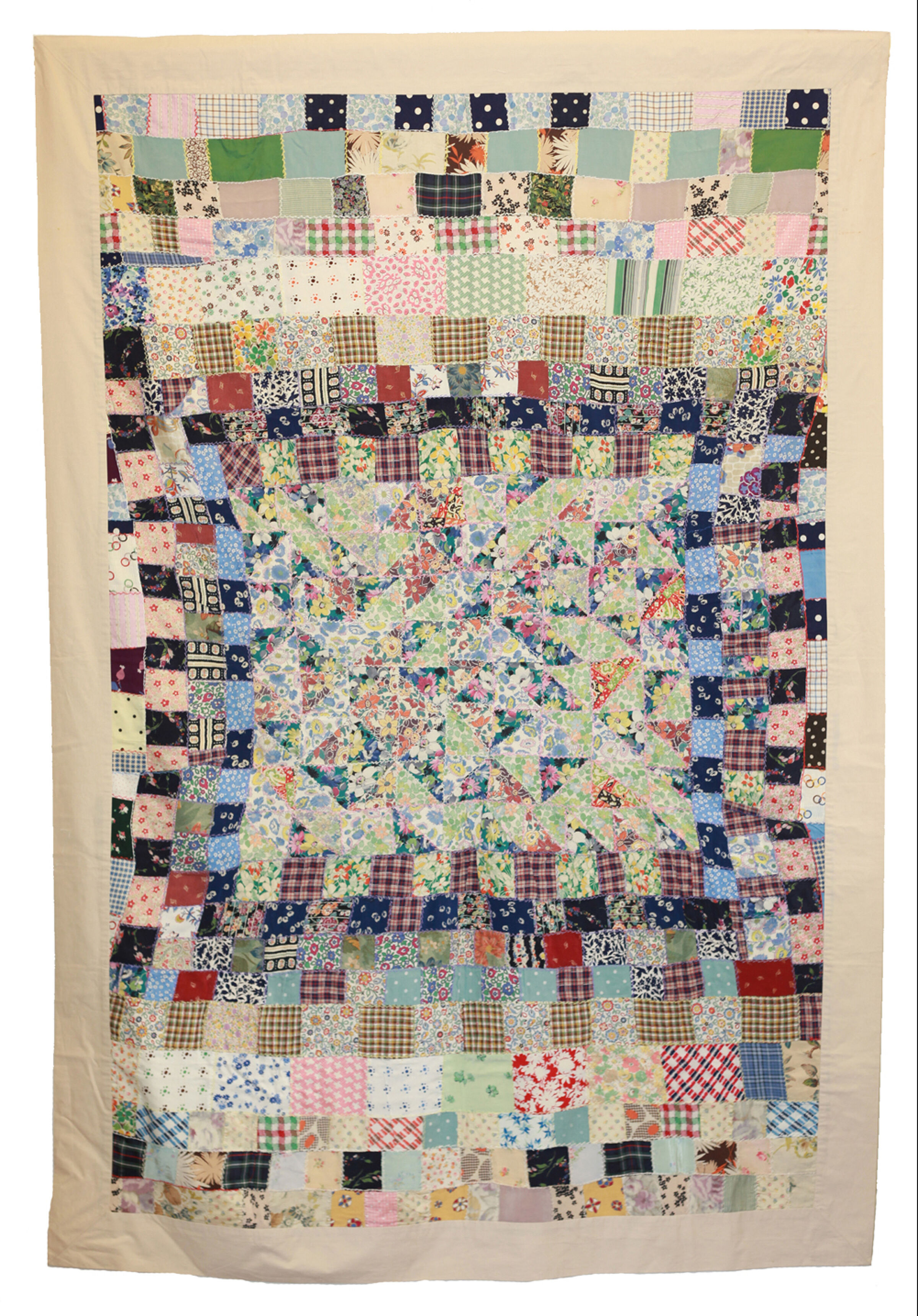 Wartime patchwork coverlet made from multicoloured fabric squares and triangles with embroidered seams and a central geometric design