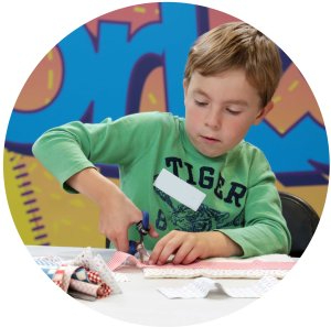 Young quilter boy cutting fabric piece