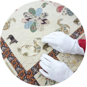 White gloved hands working on a quilt