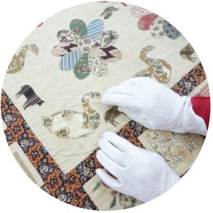 White gloved hands working on a quilt