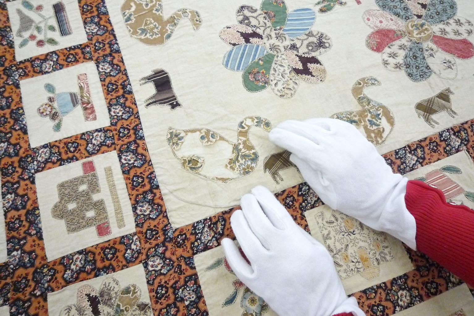 Person working on quilt wearing conservation gloves