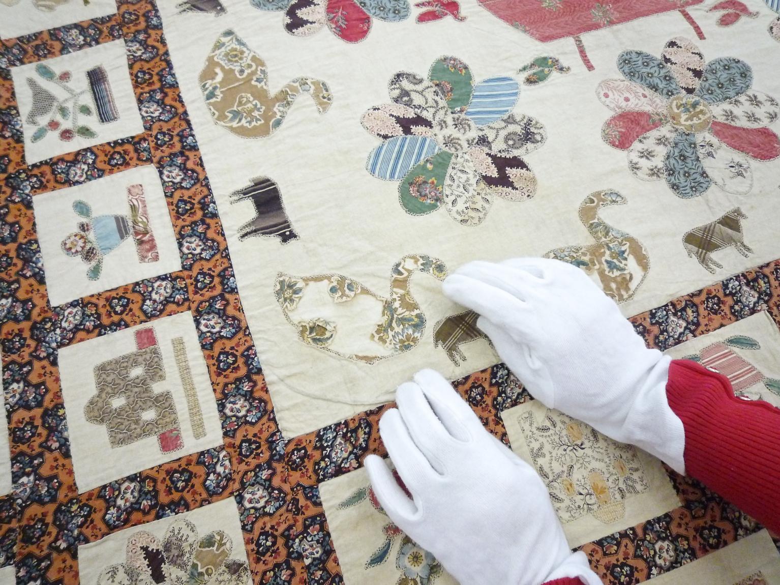 Person working on quilt wearing conservation gloves