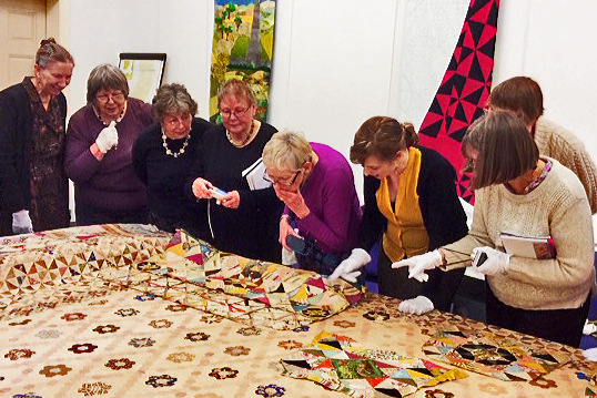 Ladies examining patchwork quilt