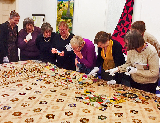 Ladies examining patchwork quilt