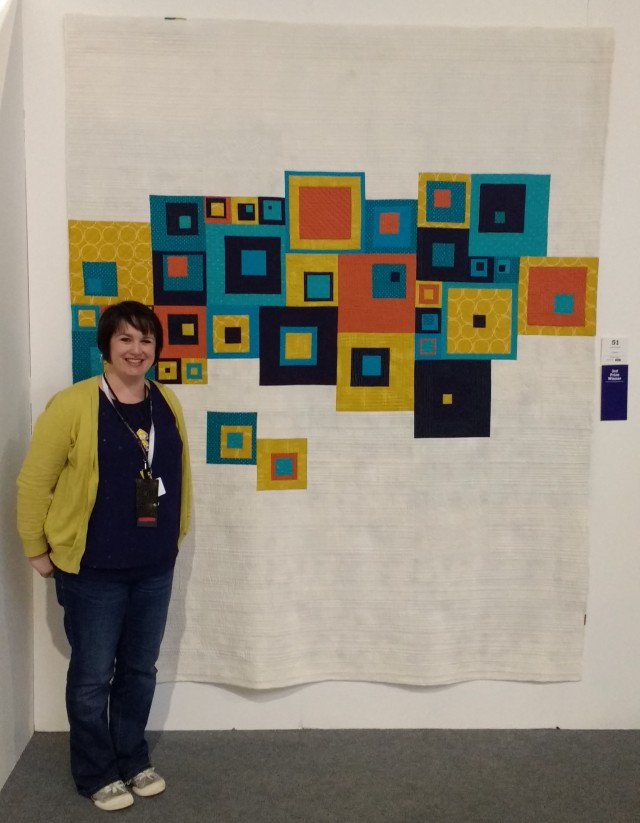 Sarah Humphreys standing next to her winning quilt - Total Squares.