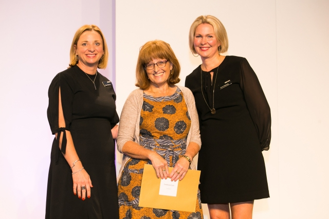 Annelize Littlefair holding prize envelope standing with judges