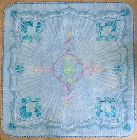 Blue and white quilt with design radiating from centre and scalloped embelishments