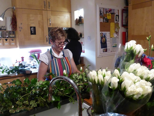 Phillipa Maylor stood at a kitchen sink surrounded my foliage and flowers