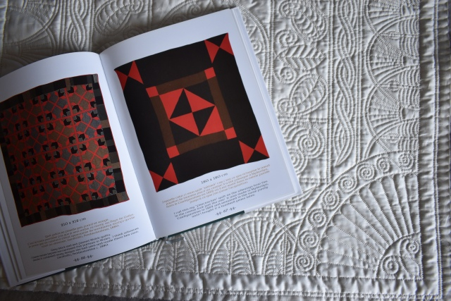 ?Les Quilts Gallois. Welsh Quilts? by Jen Jones open on a double page spread laid on a beige embroidered quilt