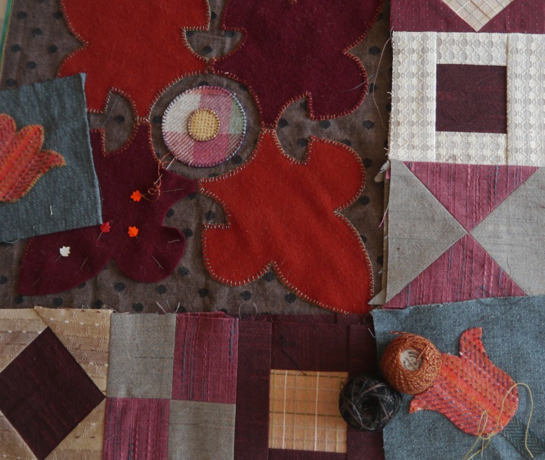 Red and grey quilt pieces laid out with 2 reels of thread