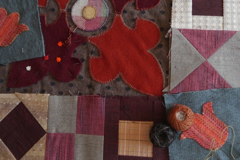 Red and grey quilt pieces laid out with 2 reels of thread