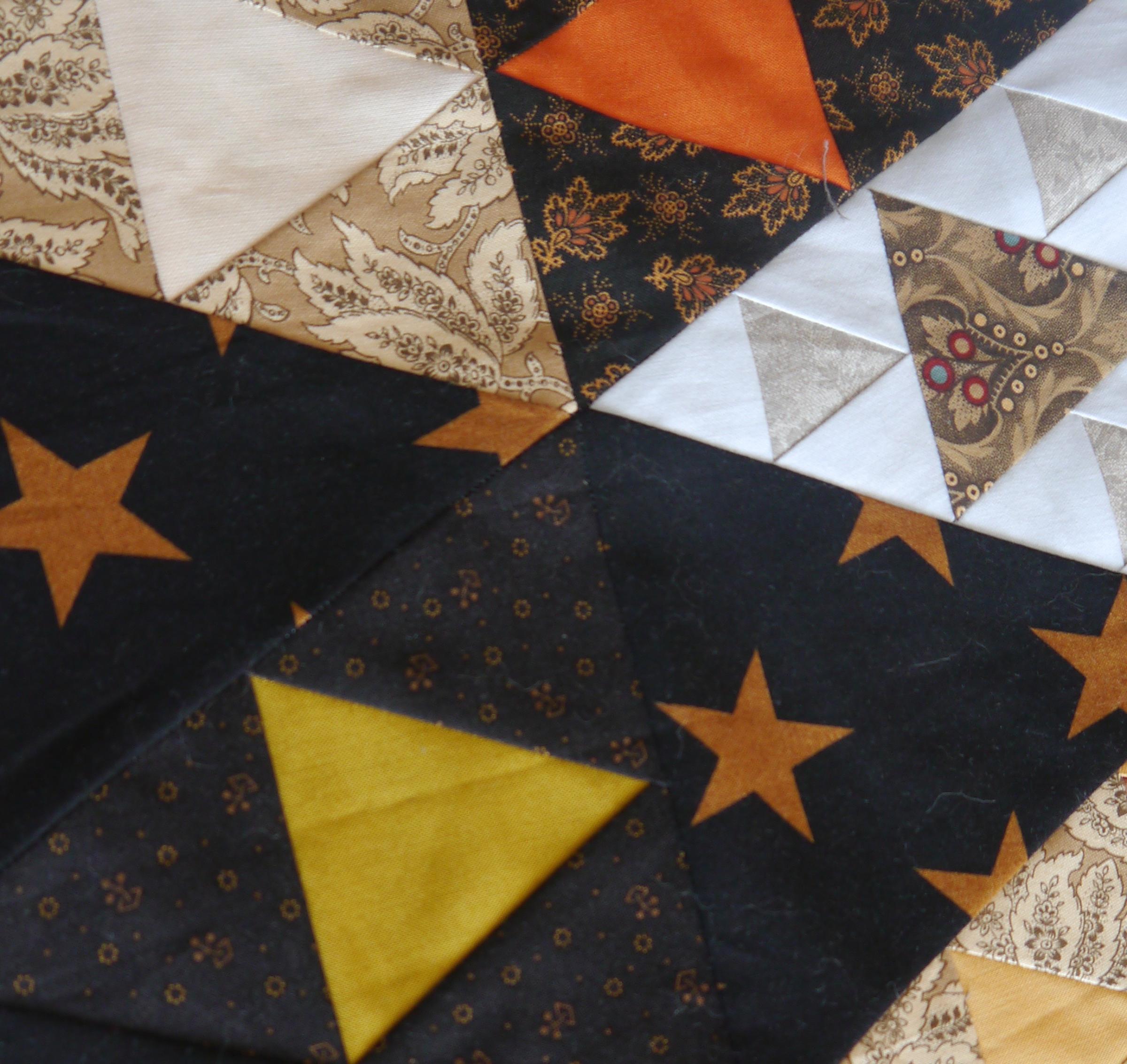 Close up of a quilt made of lots of different sized triangle pieces in many different fabrics