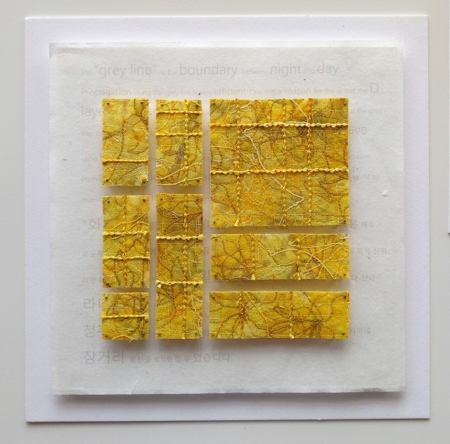 The Greyline #2 Day, 2017, by Sara Cook. Small sections of quilted fabric in different sized squares and rectangles in yellow fabric with an embroidered pattern.