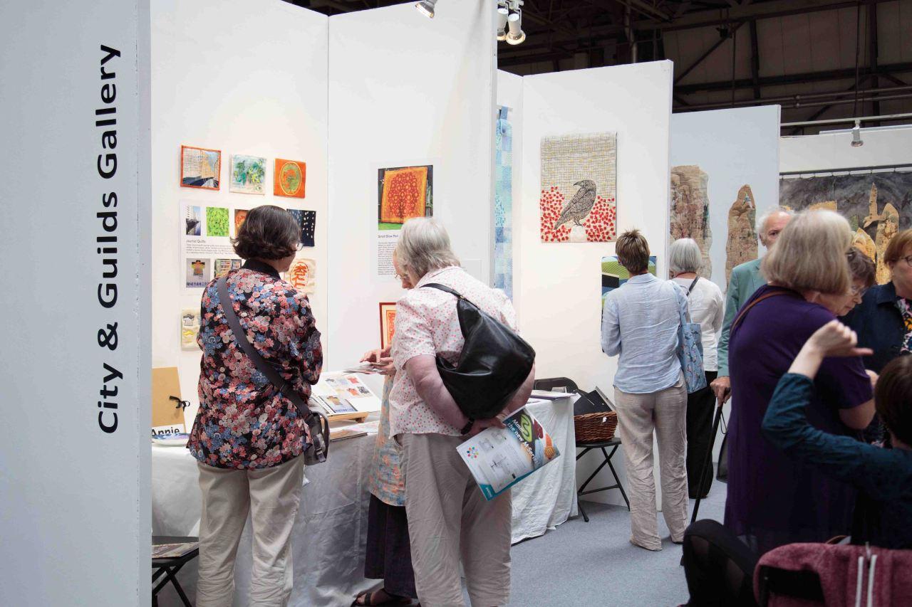 People visiting the City and Guilds Gallery stands at the Festival of Quilts