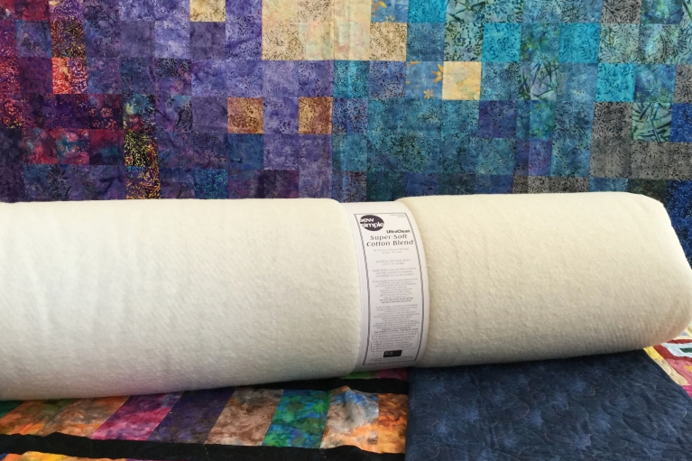 Roll of super soft cotton blend wadding on a multi-coloured surface