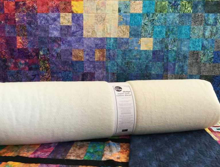 Roll of super soft cotton blend wadding on a multi-coloured surface