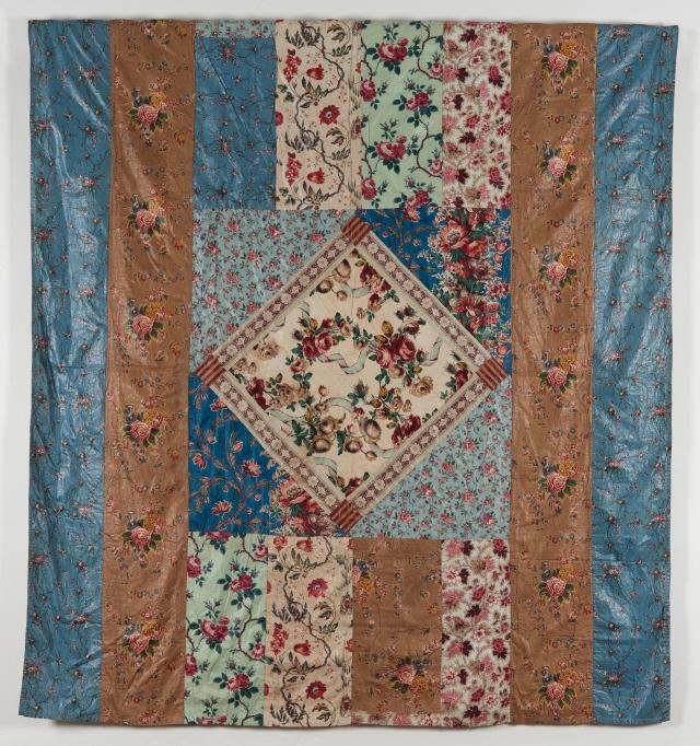 Coverlet made of rectangles in different floral patterned fabrics in blues, browns and beige