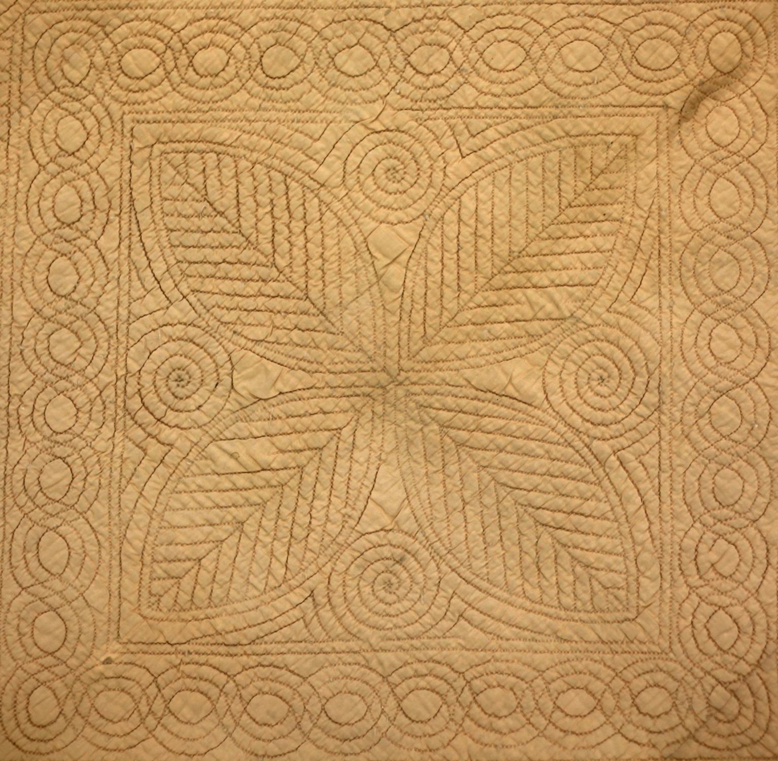 Peach coloured wholecoth quilt reversing to blue, quilted in a classic Welsh centre and defined borders layout, with typical Welsh motifs.