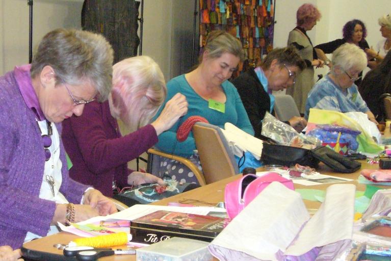 Group of women sat at a table sewing during a craft workshop.