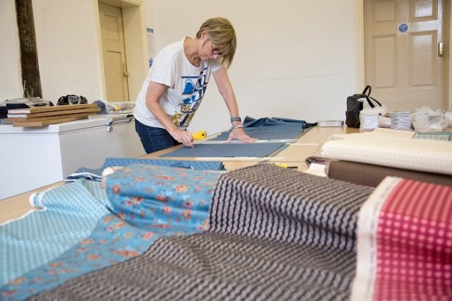 Woman cutting fabric pieces on a table.