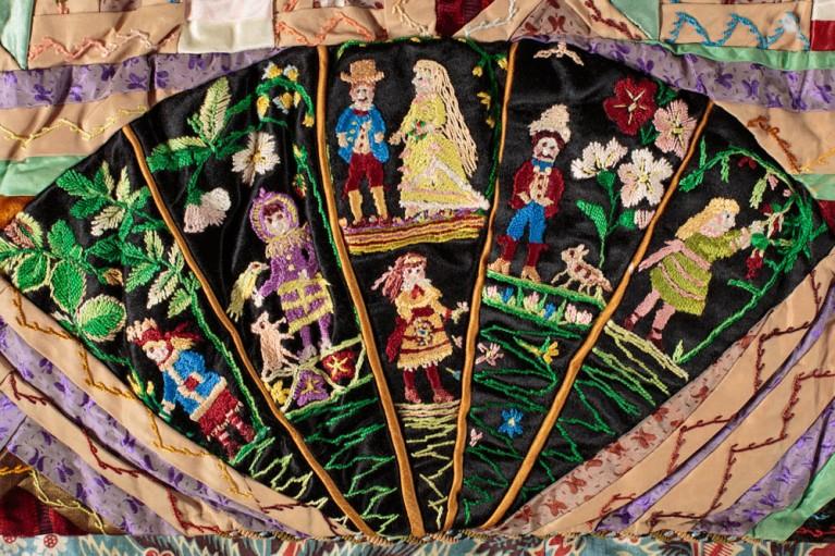 Close up of a historical quilt showing small figures in a fan shape
