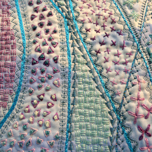 Green, blue, pink and green stitching on a white background