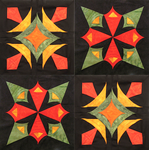 Quilt made of four square blocks each with a black background and a pattern made of green, red, orange and yellow folded fabric pieces
