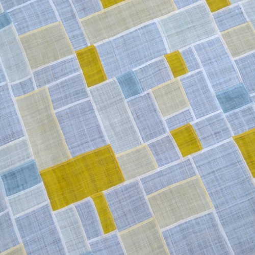 A section of quilt made using small grey, white, yellow and beige sections