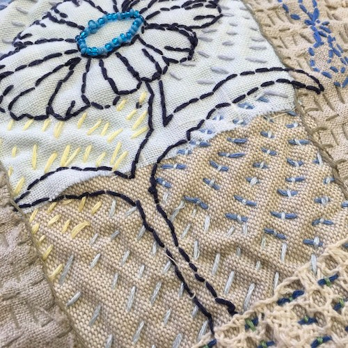 Flower stitched on calico fabric using a Kantha Stitch