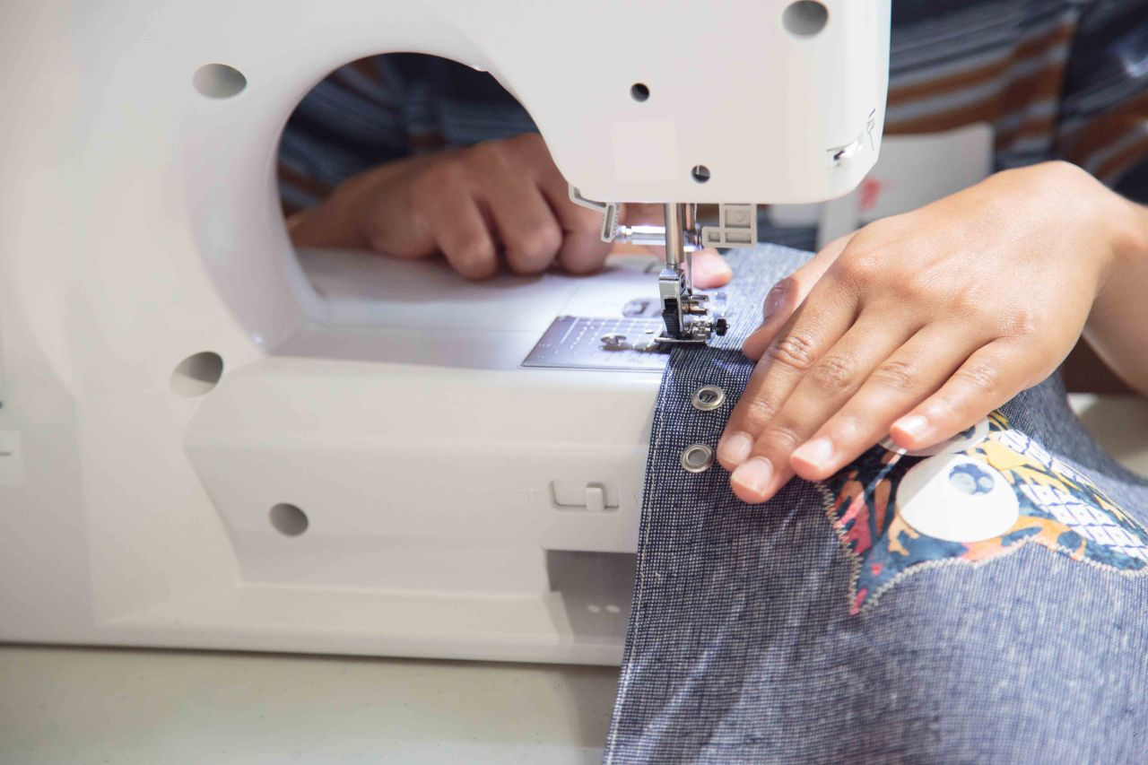 A person using a sewing machine to sew on blue fabric