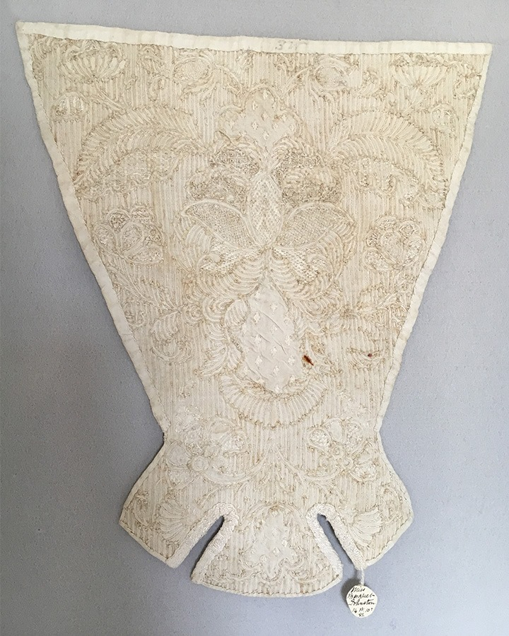 The back of a quilted stomacher shows the tufts from ends of the cords