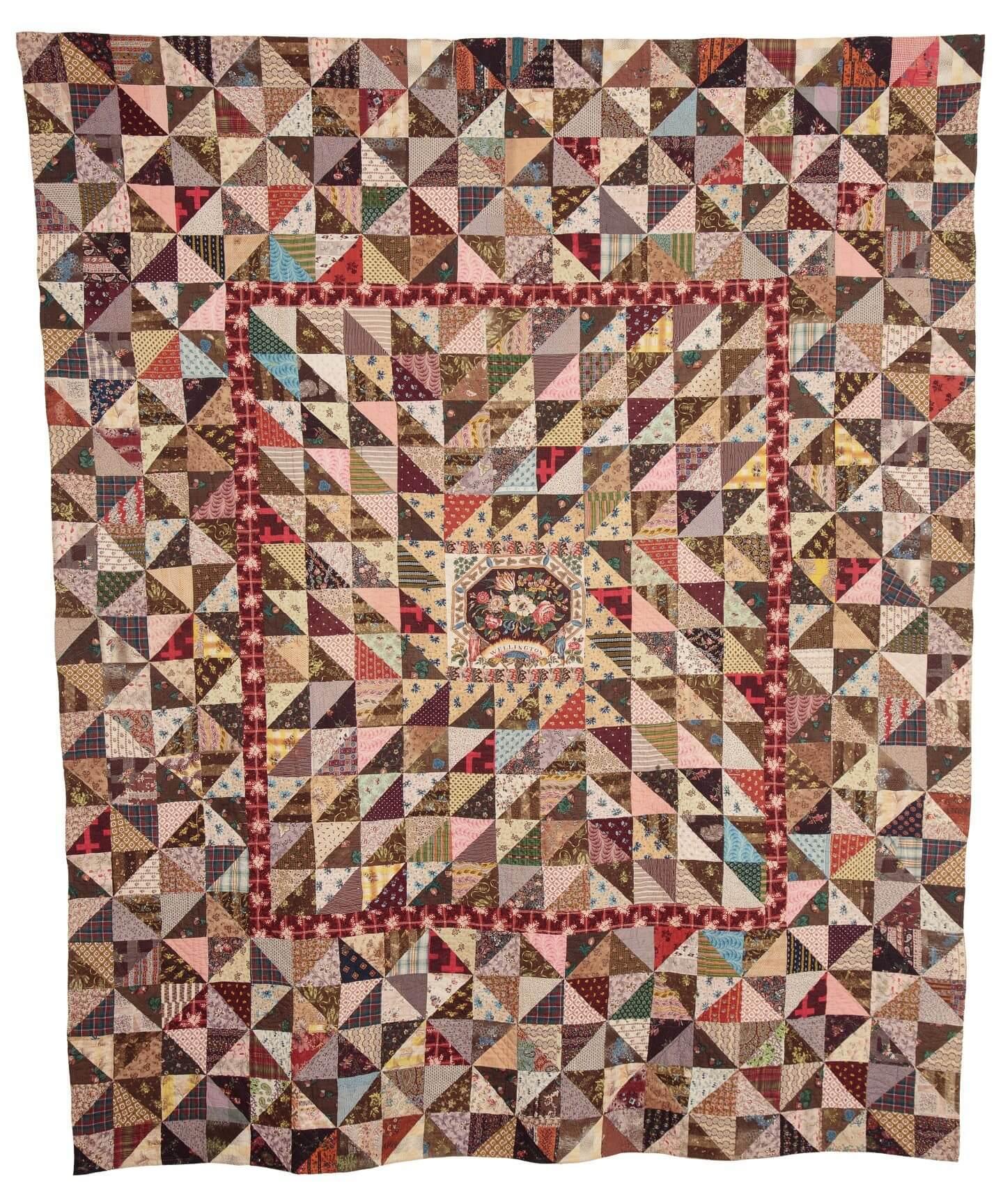 Quilt with colourful patchwork triangles design on the front with a beautiful block printed panel in the centre
