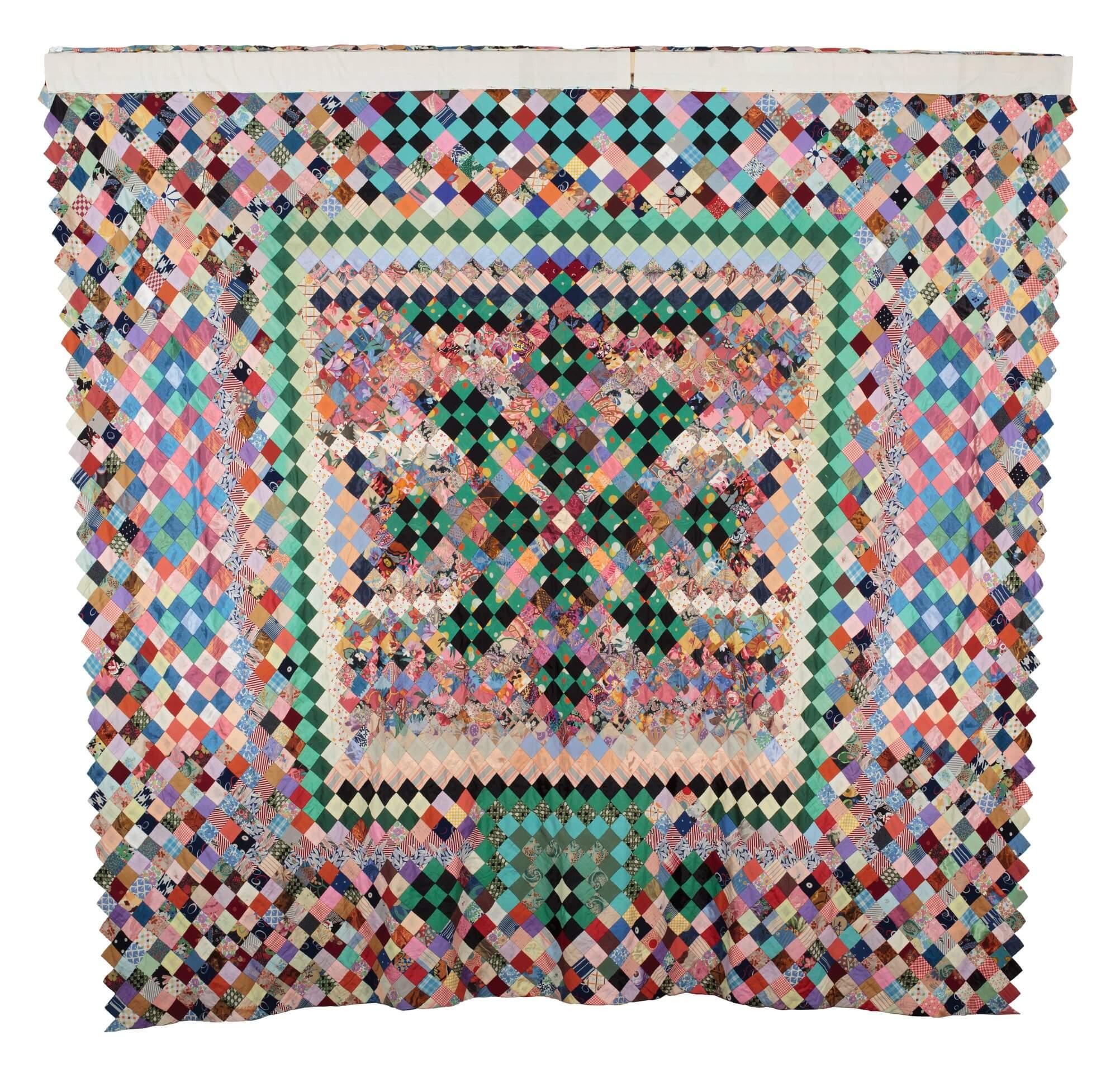 Quilt made of square patches on point with a border of larger rectangular patches set at an angle.