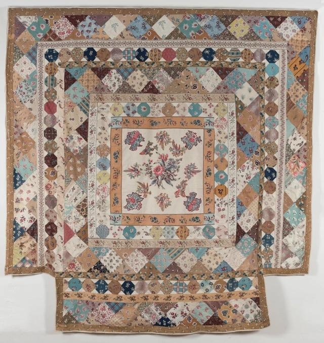 A framed printed cottons top with nine frames, around a central Broderie Perse panel. The central square contains Broderie Perse applique in large floral printed furnishing fabric, with blanket stitch around the edges.