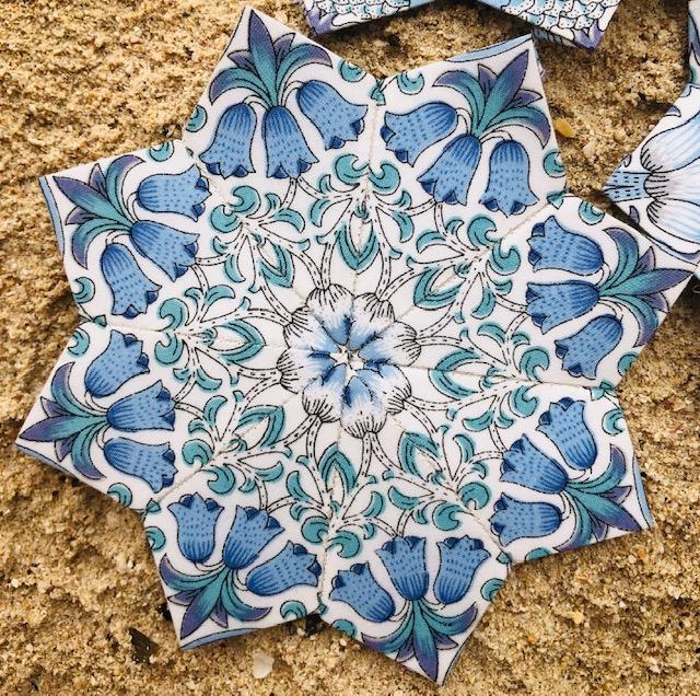 Close up of a star shaped quilt piece in light blue patterned fabric on a brown background